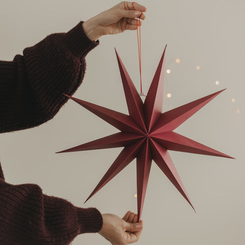 Großer roter Papierstern mit langen Spitzen und roter Aufhängung als festliche Weihnachtsdeko
