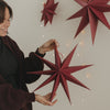 Roter Papierstern mit langen Spitzen und Aufhängung als stilvolle Weihnachtsdekoration