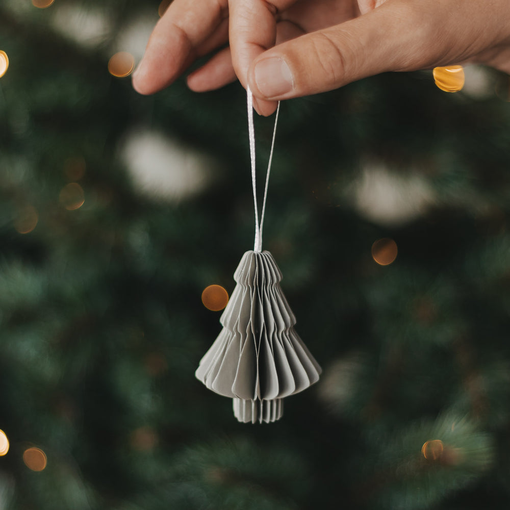 Grauer Papierbaum als Christbaumschmuck wird an den Weihnachtsbaum gehängt