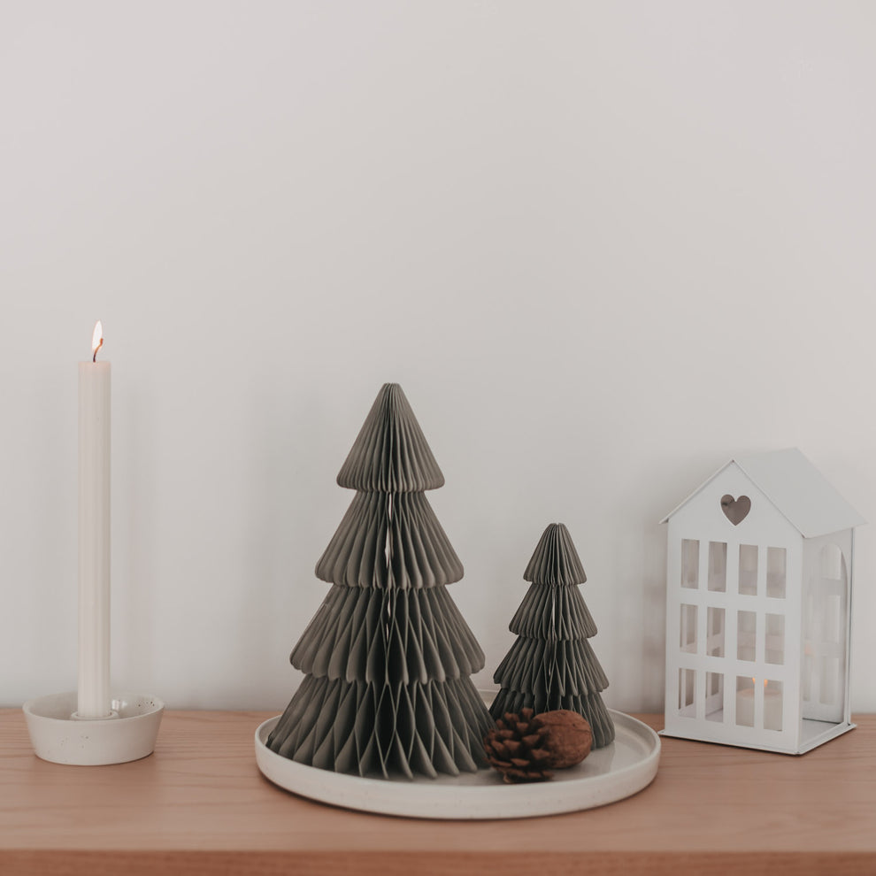 Zwei graue Papiertannen in Wabenoptik mit Kerze und Laterne als minimalistische Weihnachtsdekoration
