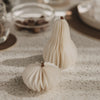 Zwei weiße Papierkürbisse in unterschiedlichen Formen als stilvolle Herbstdeko auf dem Tisch