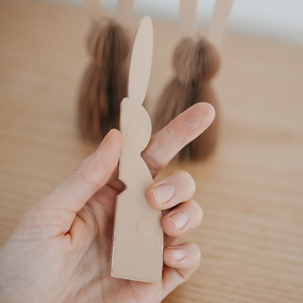 Naturfarbener Papierhase flach zusammengelegt in der Hand, Detailansicht der Schnittform.