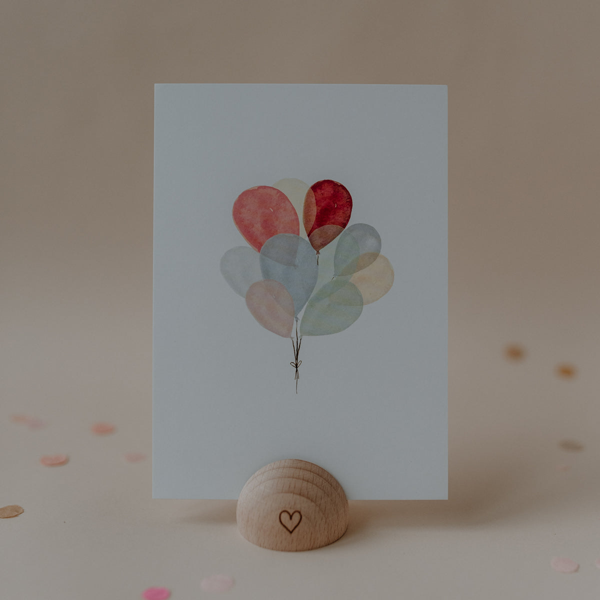 Eulenschnitt Aquarellkarte mit bunten Luftballons in zarten Pastellfarben, aufgestellt in einem Kartenhalter aus Holz.