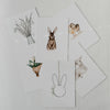 Oster-Kartenset mit sechs Aquarellmotiven locker ausgelegt: Hase, Lamm, Küken, Tulpen und Weidenzweige.