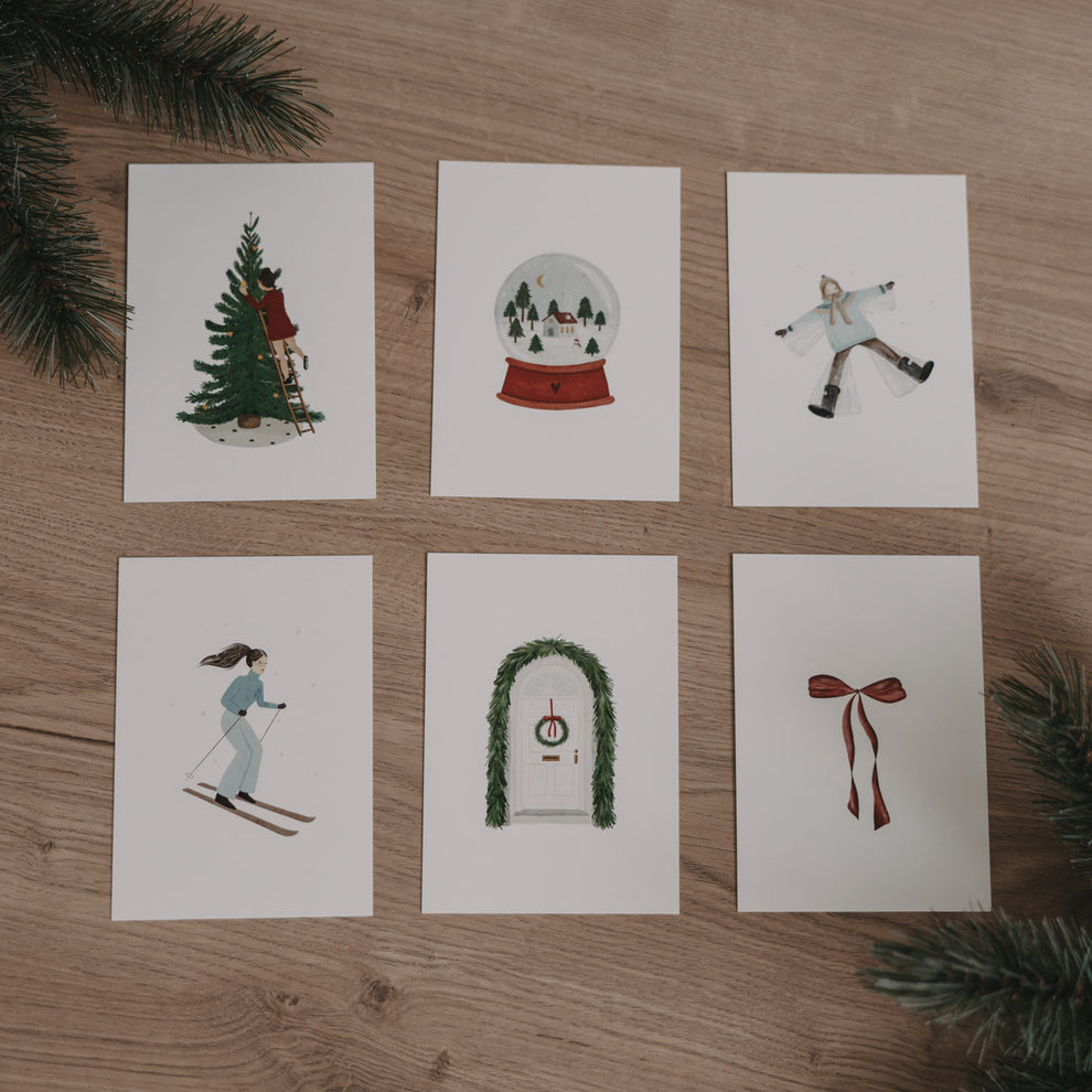 Sechs Weihnachtskarten aus dem Set "Christmas Love" mit winterlichen Motiven auf hellem Holz und Tannenzweigen