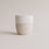 Minimalistischer Keramikbecher mit Sternprägung vor hellem Hintergrund