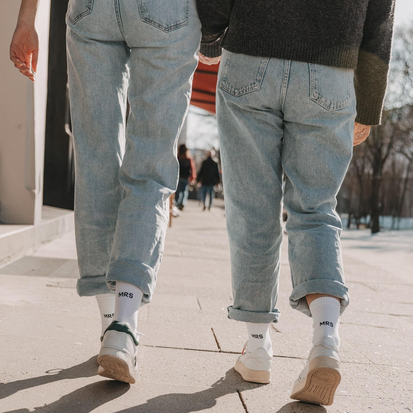 Zwei Personen mit weißen „MRS“ Socken gehen gemeinsam auf Straße