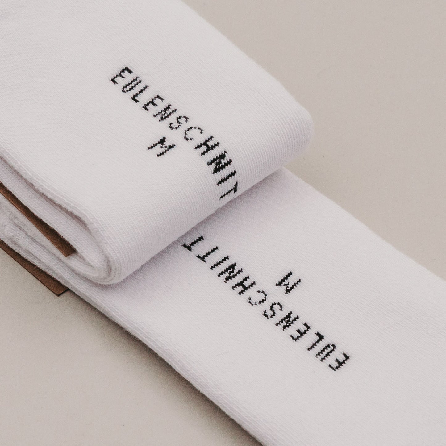 Gefaltete weiße Socken „MRS“ mit Eulenschnitt Branding im Detail