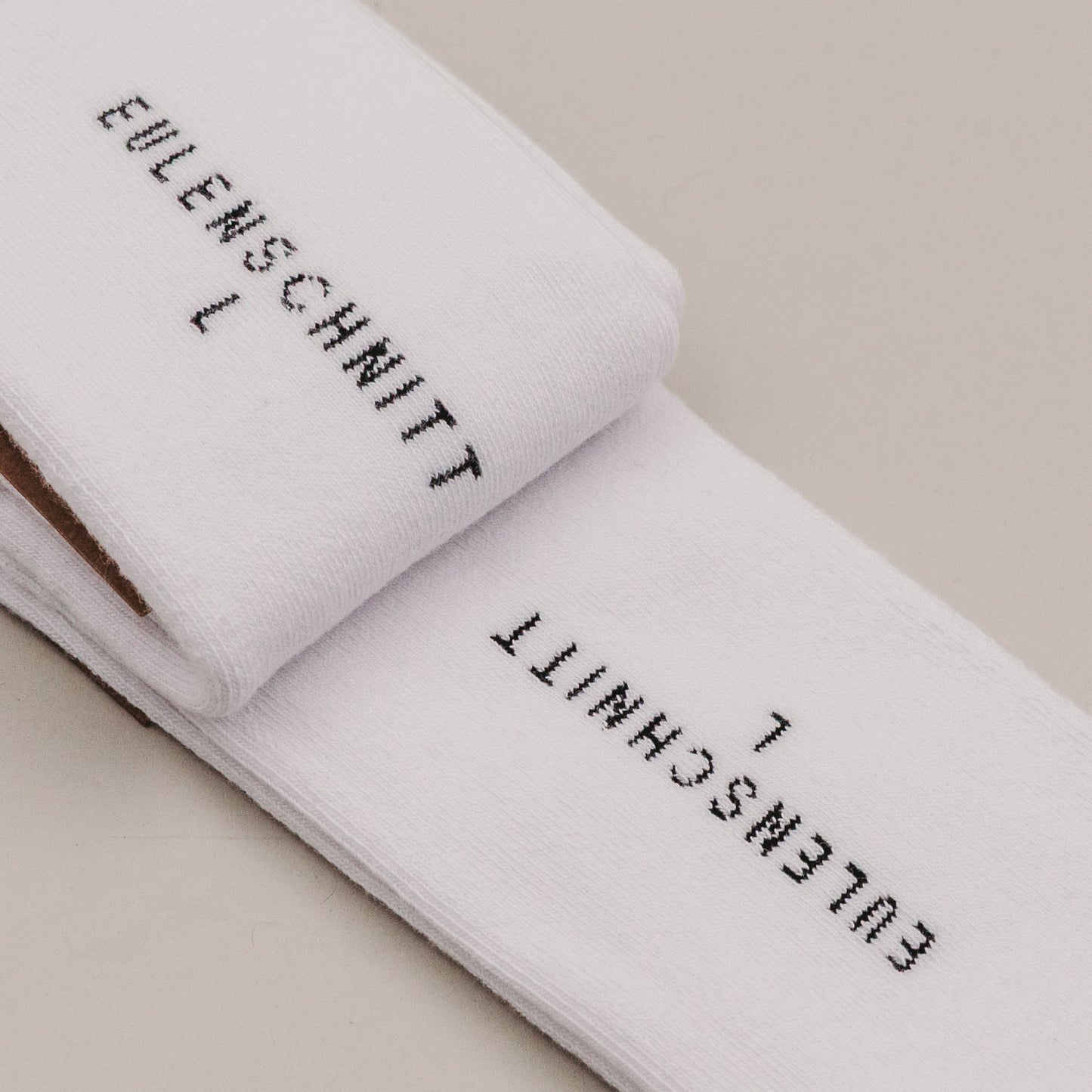 Gefaltete weiße Socken „Erstmal Kaffee“ mit Eulenschnitt Branding Detail