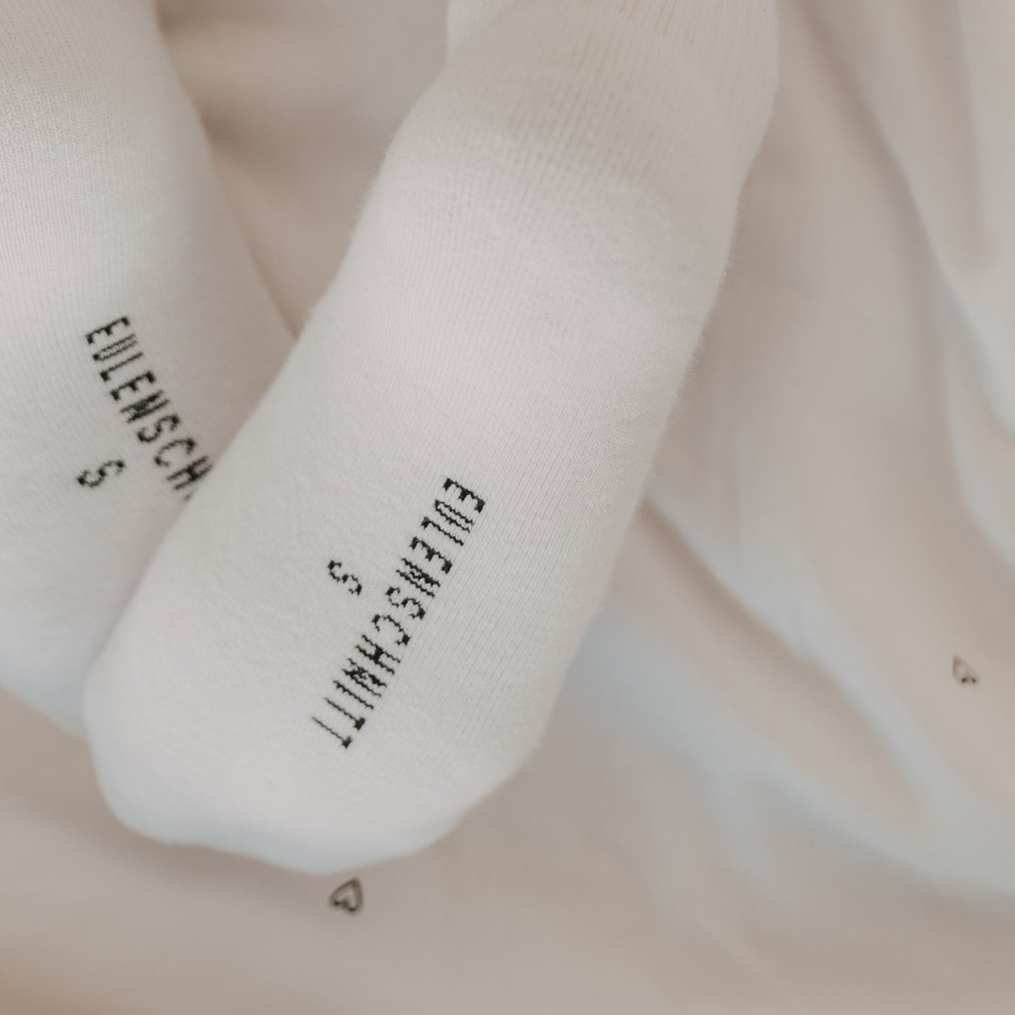 Weiße Socken mit Eulenschnitt Logo an der Sohle in ruhiger, minimalistischer Darstellung