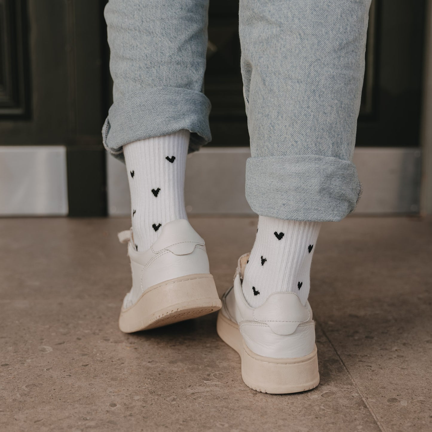 Weiße Herz-Socken von hinten getragen mit hochgekrempelter Jeans und Sneakern