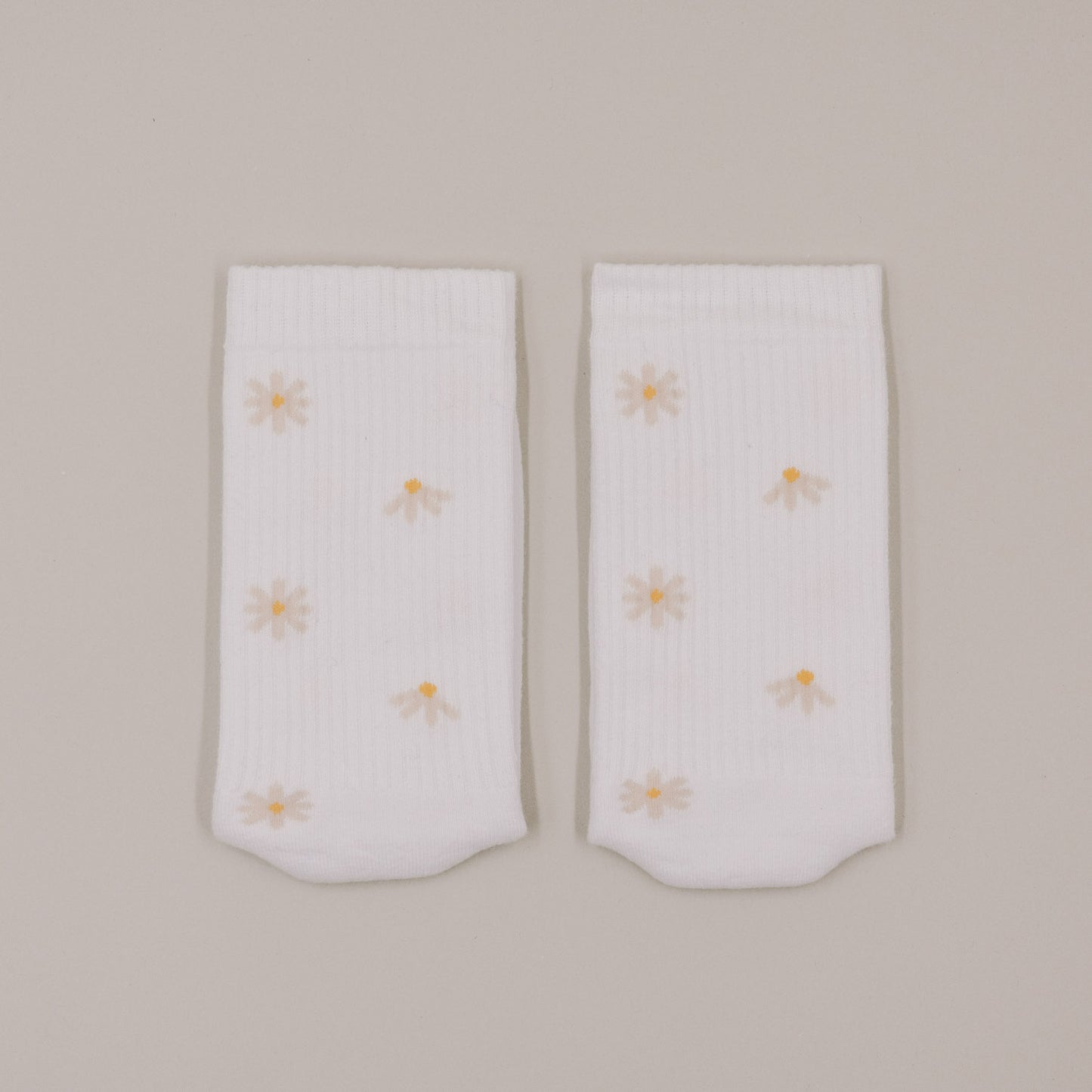 Flachliegende weiße Socken mit feinem Gänseblümchen-Muster minimalistisch dargestellt