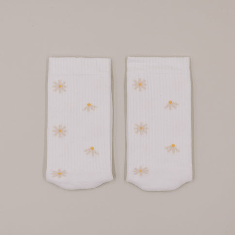 Flachliegende weiße Socken mit feinem Gänseblümchen-Muster minimalistisch dargestellt