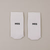 Flachliegende weiße Socken mit „MRS“ Schriftzug minimalistisch dargestellt