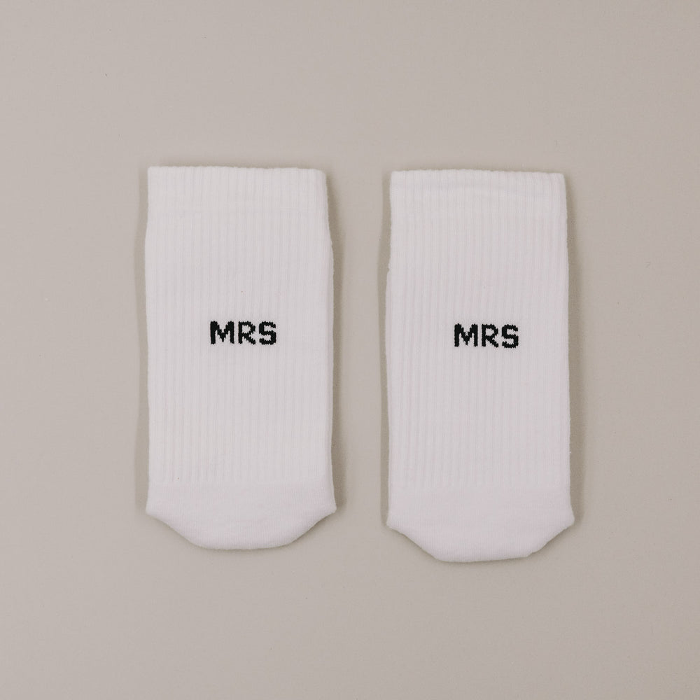Flachliegende weiße Socken mit „MRS“ Schriftzug minimalistisch dargestellt