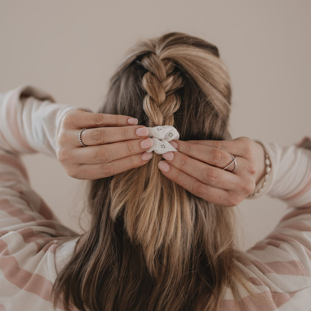 Detail geflochtener Zopf mit weißem Scrunchie mit Smiley-Muster