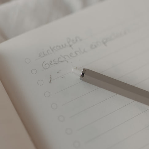 Grauer Druckbleistift radiert Text auf Notizseite mit integriertem Radiergummi.