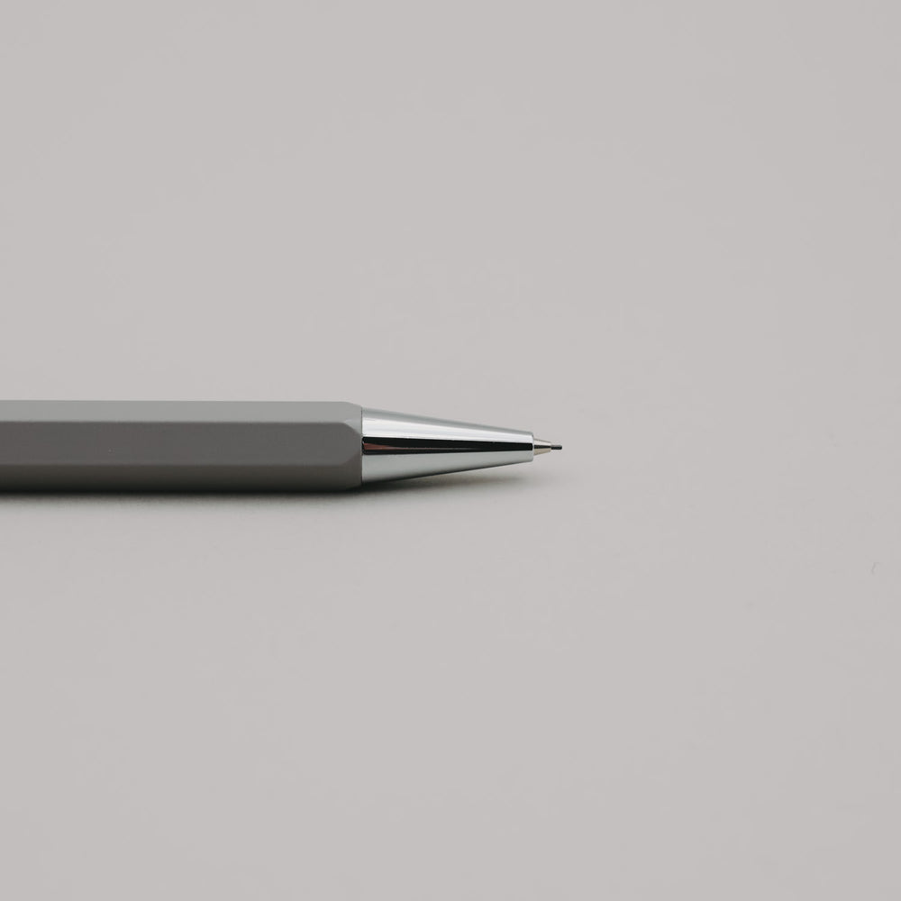 Grauer Druckbleistift mit silberner Spitze auf hellem Hintergrund, minimalistisch und elegant.