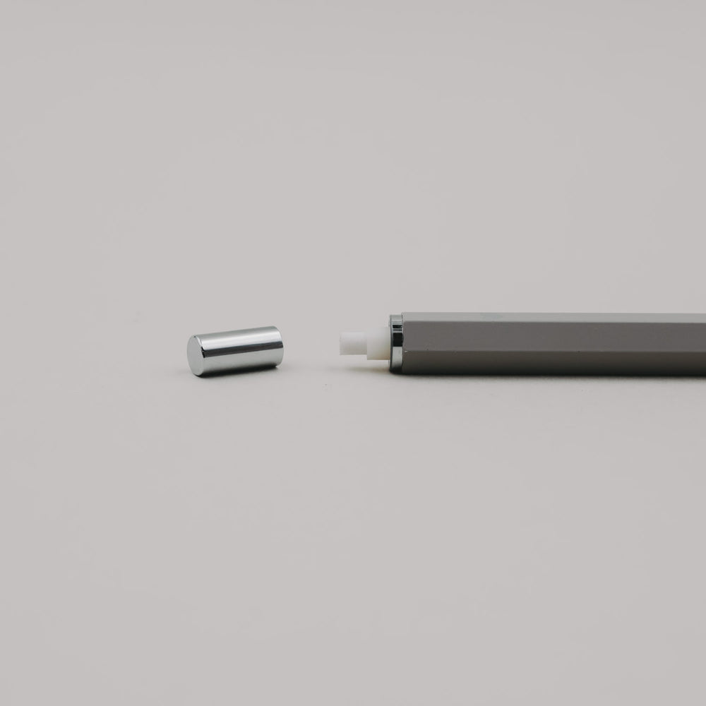 Grauer Druckbleistift mit abgenommener Kappe, sichtbar integriertem Radiergummi im Drücker.