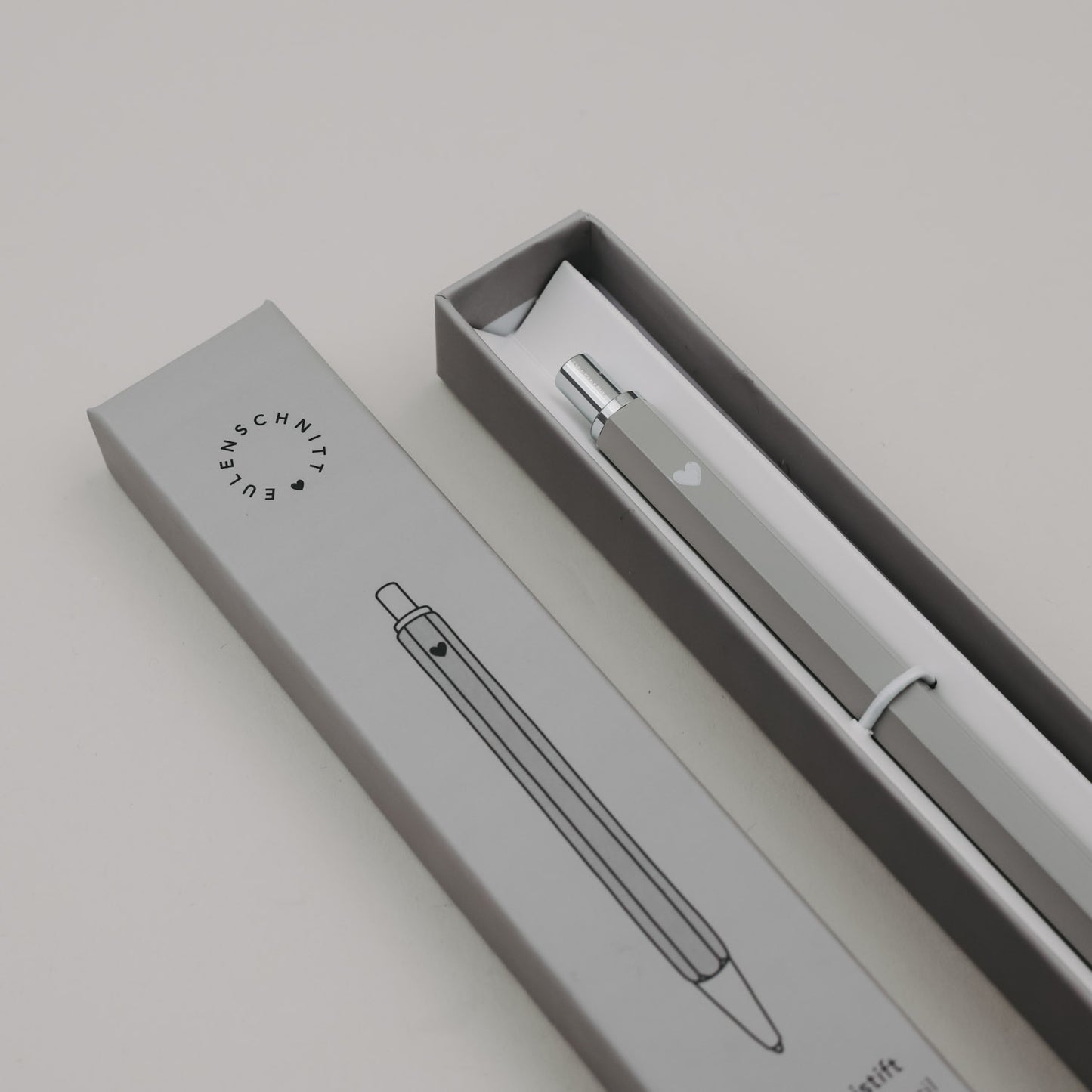 Grauer Druckbleistift in Geschenkbox mit schlichtem Design und Herzmotiv.