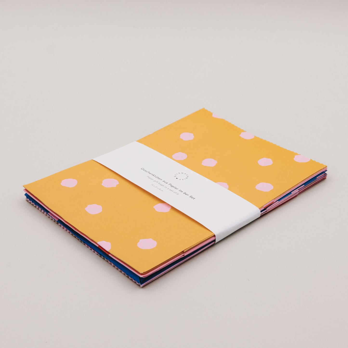 Papier-Geschenktüten im Set, flach liegend gebündelt, mit Punktmuster in Gelb und Rosa