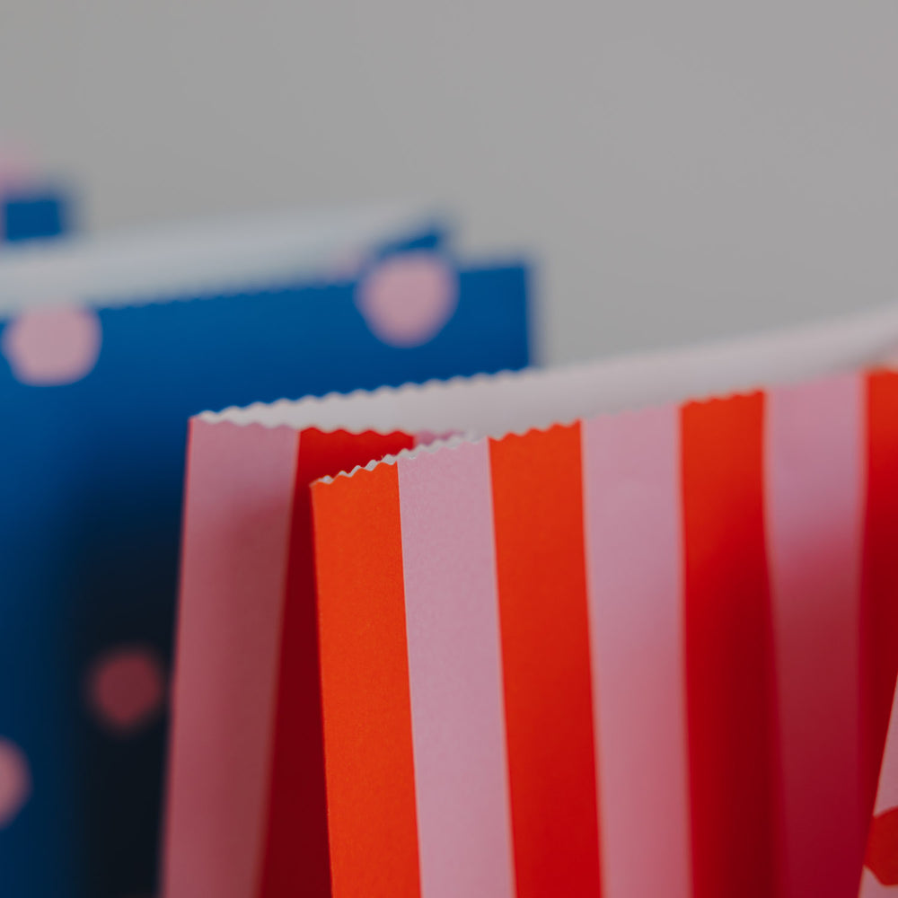 Detailansicht von Papier-Geschenktüten mit Streifenmuster in Rosa und Rot, hochwertige Verarbeitung