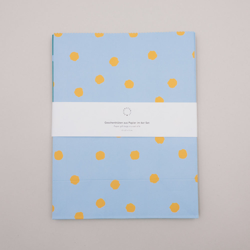 Flach liegende Papier-Geschenktüten mit Punkten im Set, gebündelt mit Banderole