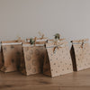 Papier Geschenktüten mit Herz-, Smiley- und Blumenmotiven im Set, dekorativ aufgereiht auf Holztisch