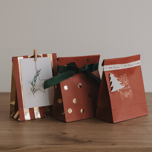 Weihnachtliche Papiertüten in Rot mit goldenen Punkten, Schleife und Anhänger, festlich dekoriert