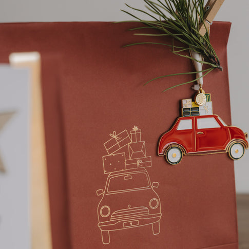 Detailansicht Papiergeschenktüte in Rostrot mit goldener Autoillustration und dekorativem Anhänger
