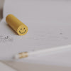 Radiergummi Smiley in Gelb auf Notizblock und Stift