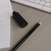 Zwei schwarze Radiergummis in Herzform neben Notizblock und Bleistift