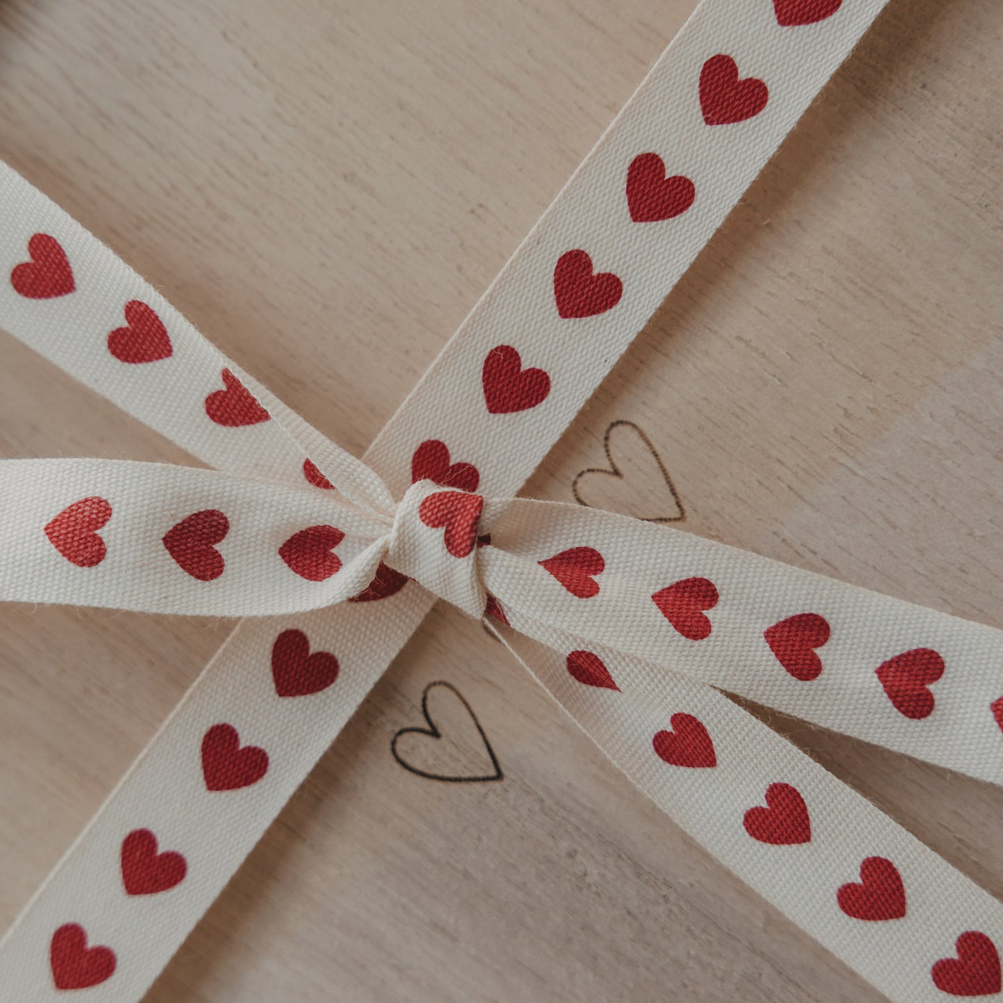 Geschenkband mit roten Herzen als Schleife auf einer hellen Holzbox