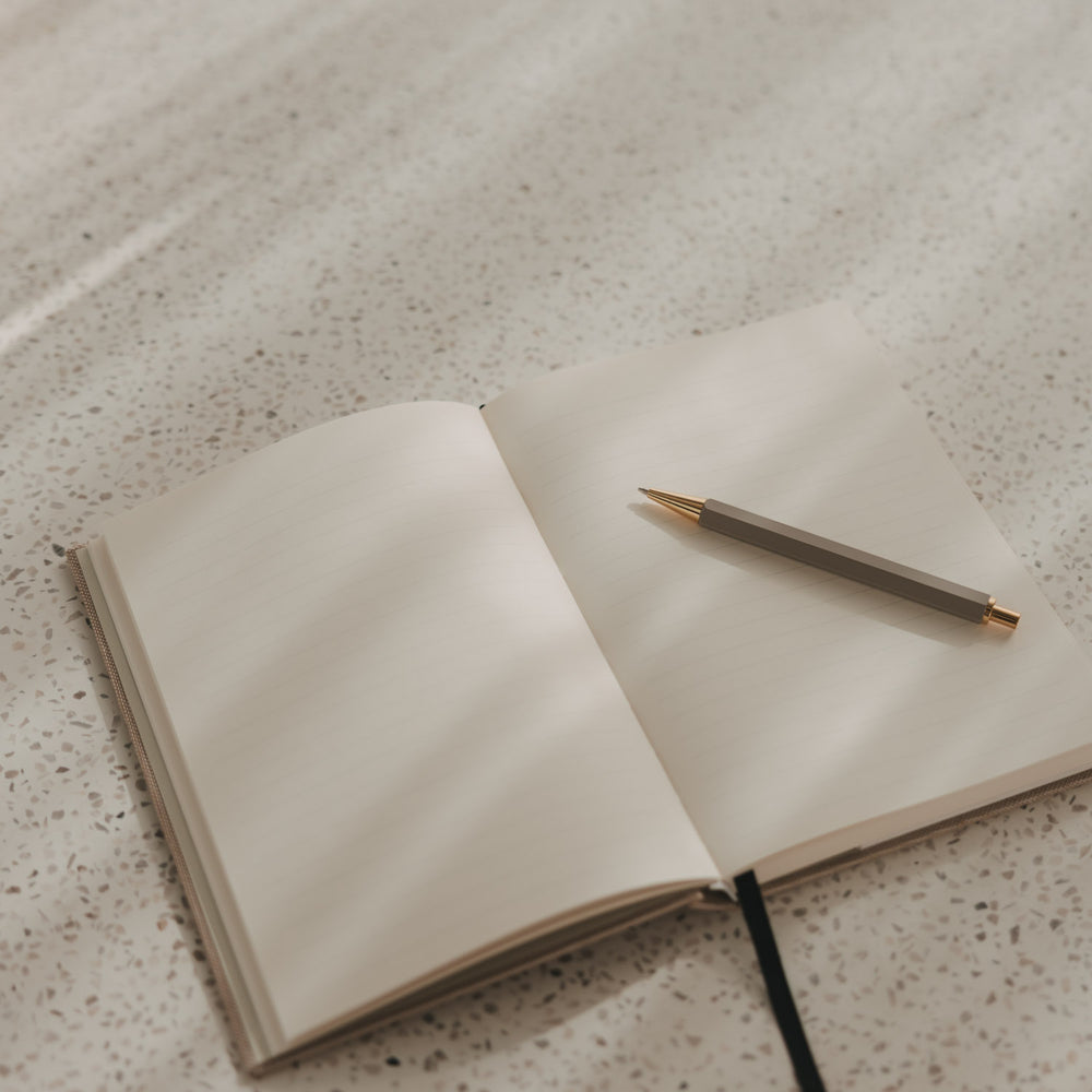 Offenes A5 Notizbuch mit linierten Seiten, schwarzem Leseband und Stift
