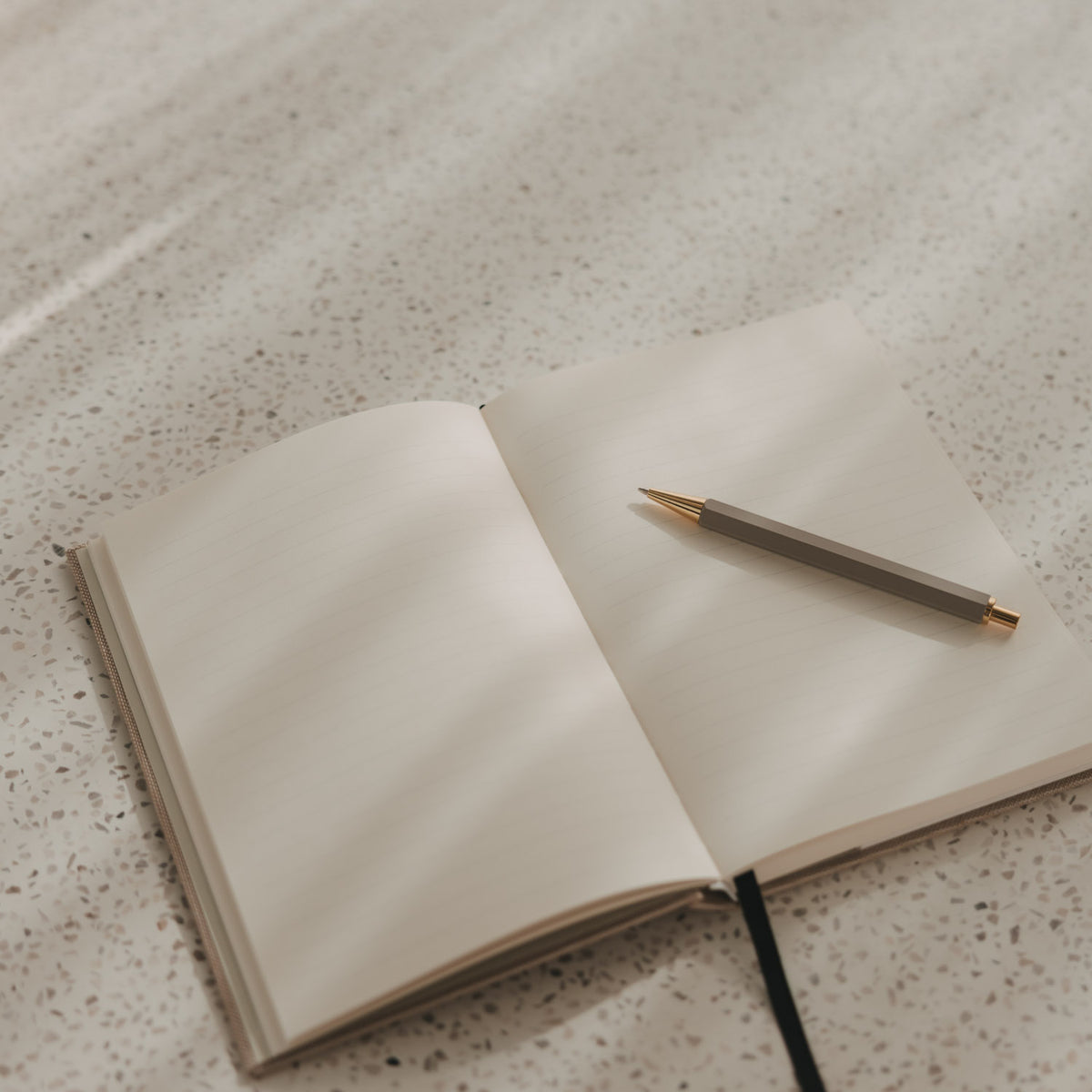 Offenes A5 Notizbuch mit linierten Seiten, schwarzem Leseband und Stift