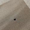 Detail des grau beigen Stoffeinbands vom karierten A5 Notizbuch mit kleinem schwarzem Herz