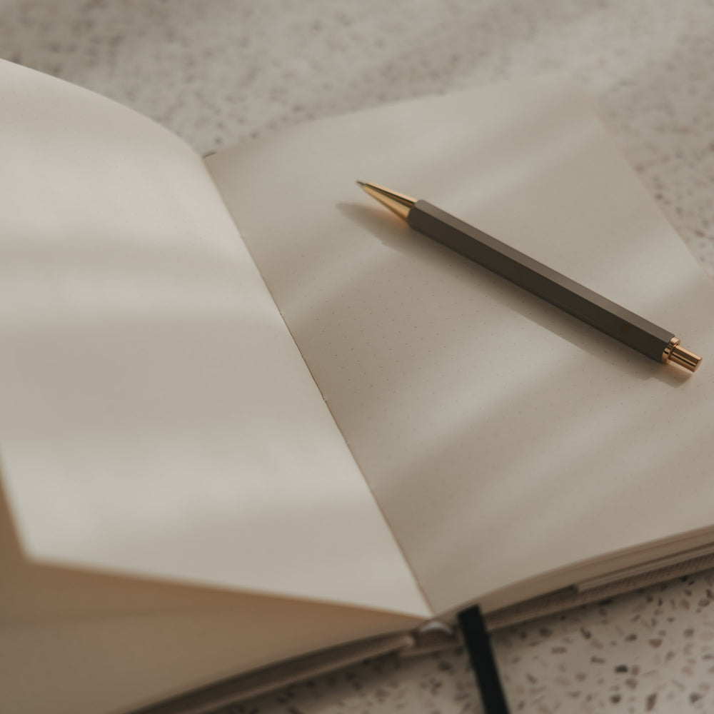 Offenes gepunktetes A5 Notizbuch mit Stift auf einer Seite
