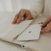Offenes Buch mit Blankoseiten und Einstecktasche für Erinnerungen, Karten und Fotos