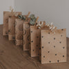 Geschenkbeutel aus Kraftpapier mit schwarzem Herzmuster, dekorativ gefaltet und mit Trockenblumen verziert